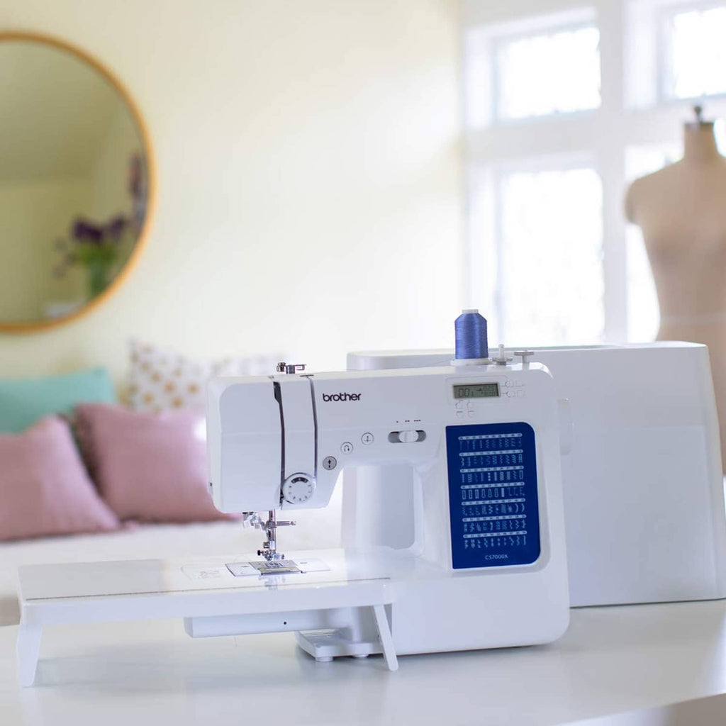White sewing and quilting machine on tabletop with fabric under presser foot
