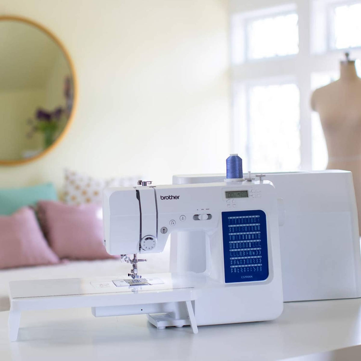 White sewing and quilting machine on tabletop with fabric under presser foot