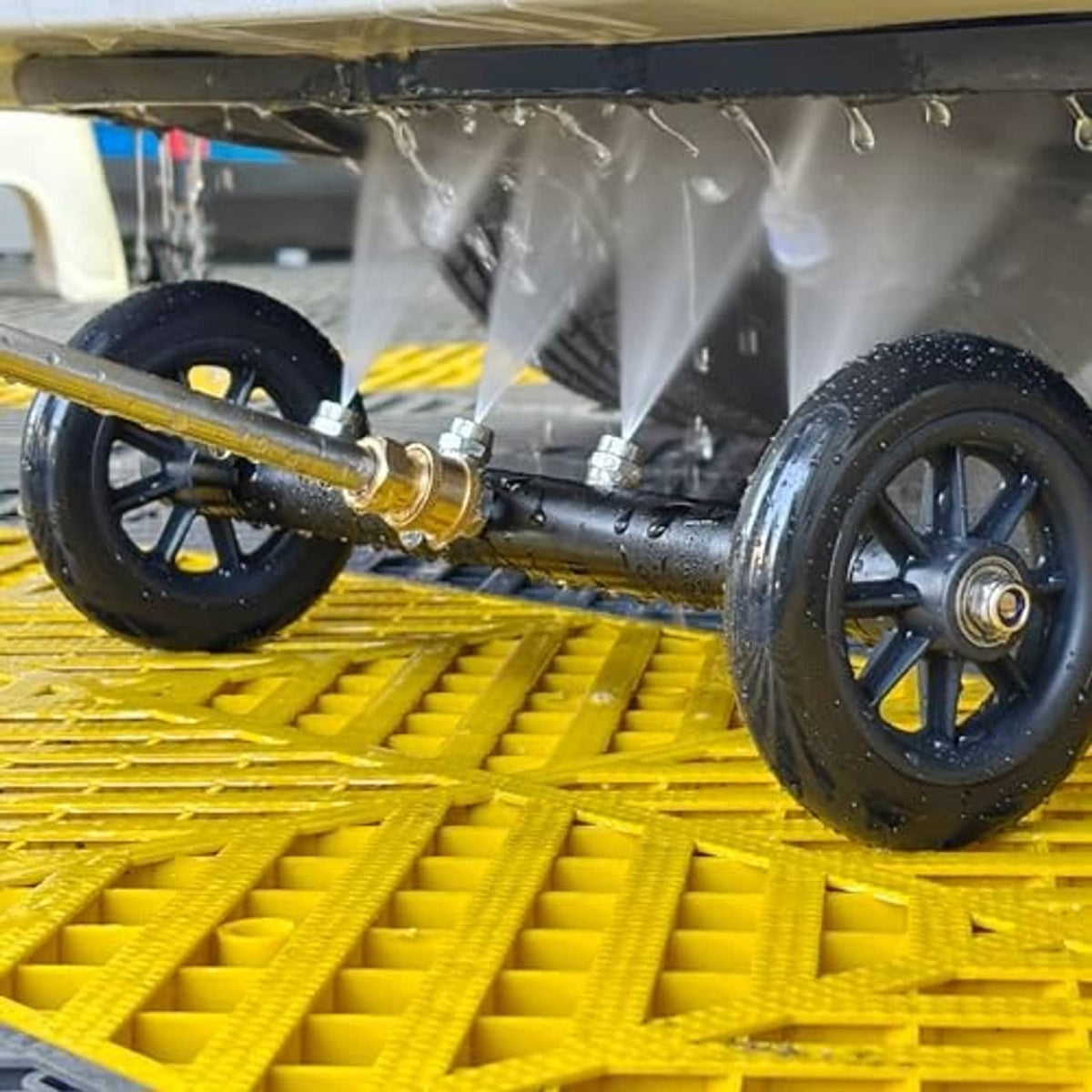 Undercarriage pressure washer cleaner with wheel bar spraying underside on a yellow rack