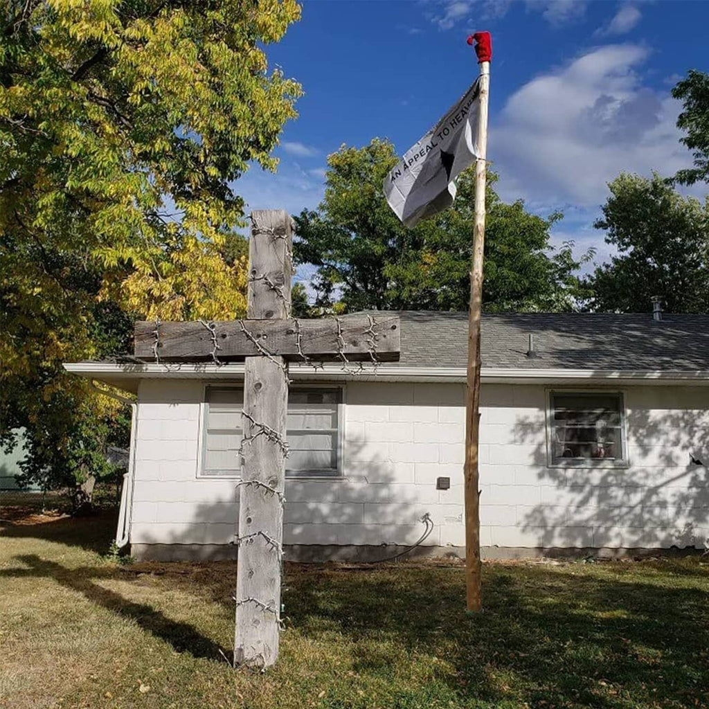 Outdoor flag flying on pole with 'AN APPEAL TO HEAVEN' and green tree design