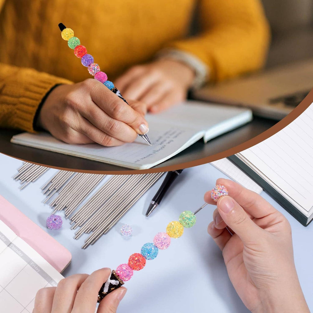 Hands using beadable pen extender rods with colorful bead segments on a desk