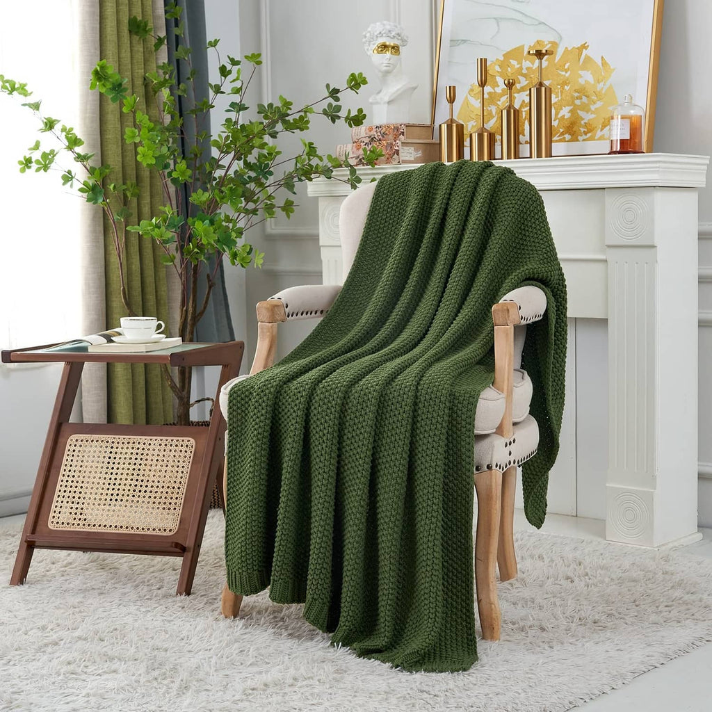 Olive green chunky cable knit throw blanket draped over a chair