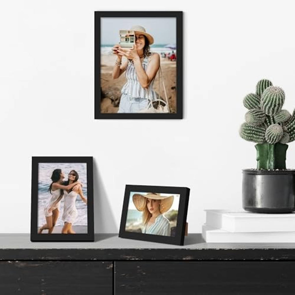 Black picture frames arranged on a console table with three displayed photos