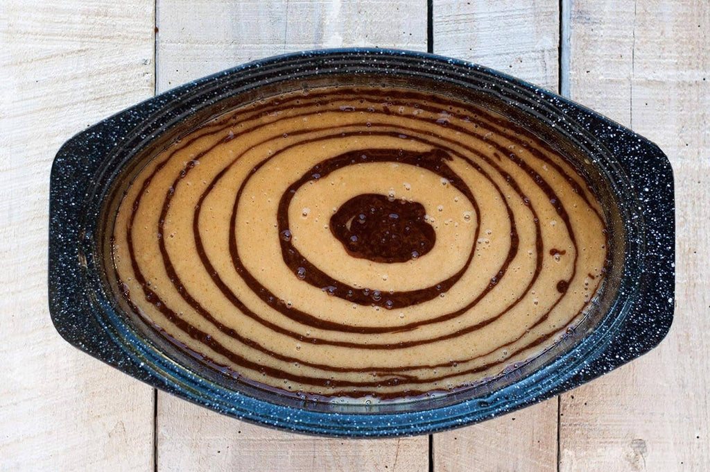 Black speckled oval roasting pan with lidless surface, topped with spiral onion rings