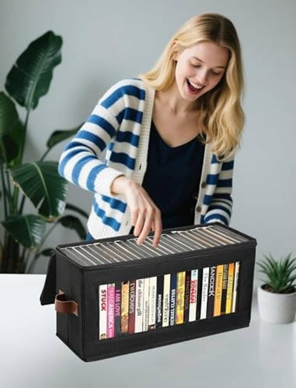 Black zip-lid DVD storage box with handle, open top as DVDs are being placed in