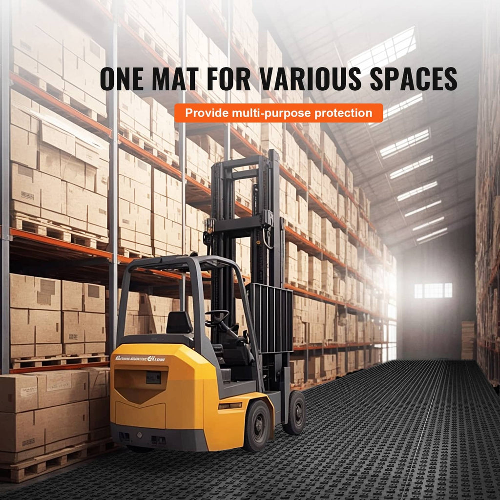 Black interlocking floor mat system with diamond tread, shown in a warehouse setting