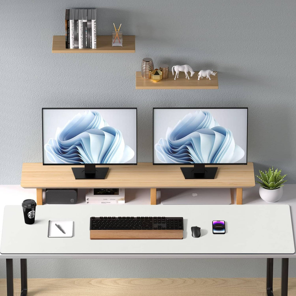 Off-white desk pad protector on double monitor desk with keyboard and small accessories.