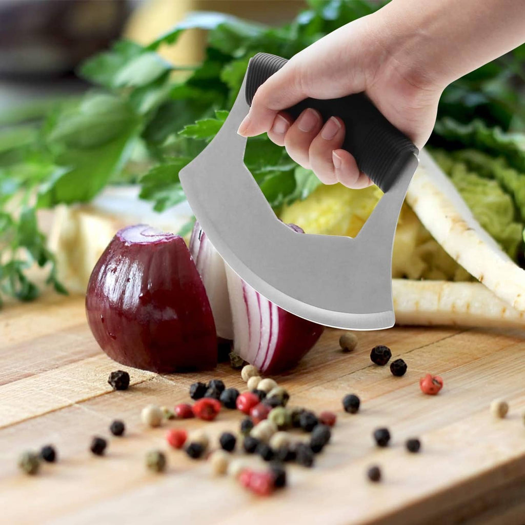 Hand holding a salad chopper with black grip and curved stainless blade on cutting board