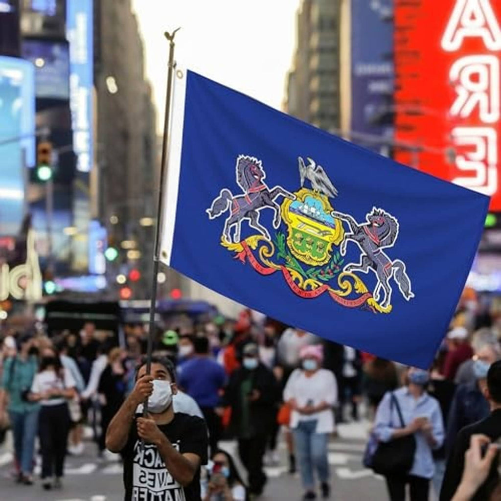 Blue embroidered Pennsylvania state flag waving in city street, horses and coat of arms