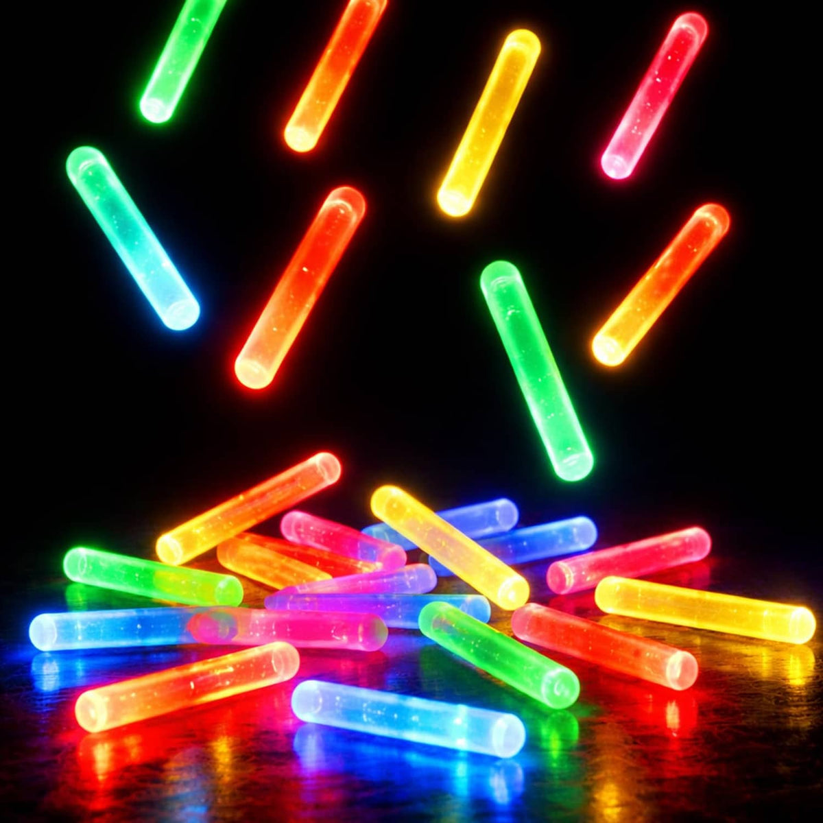 Assorted mini glow sticks, scattered and glowing in green, yellow, red, blue, pink
