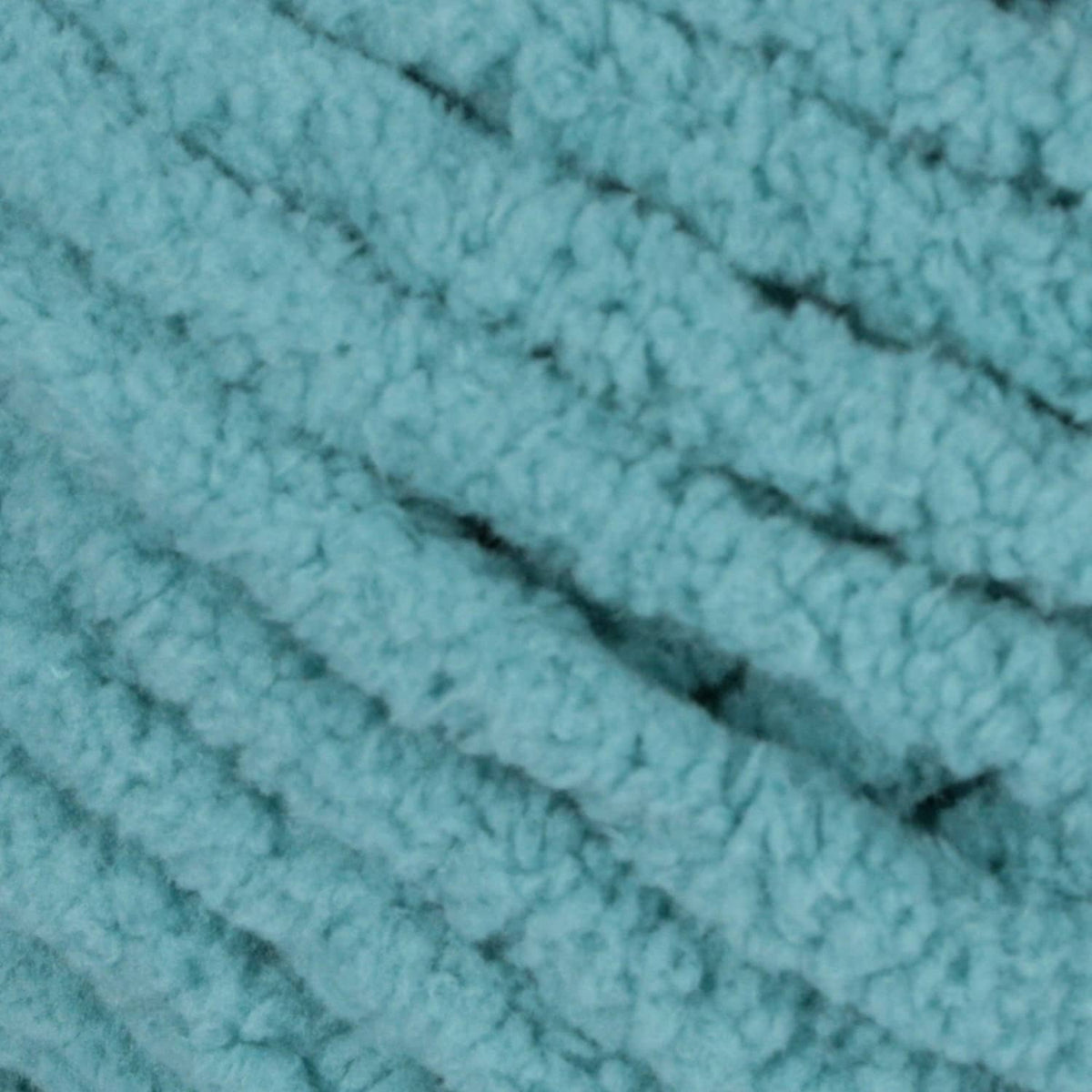 Close-up of light teal chenille yarn knit texture with thick loops