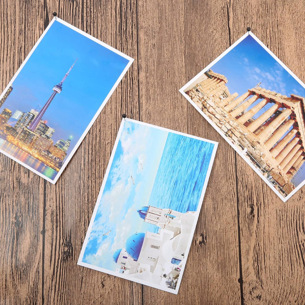 Black push pins securing photos to a board.