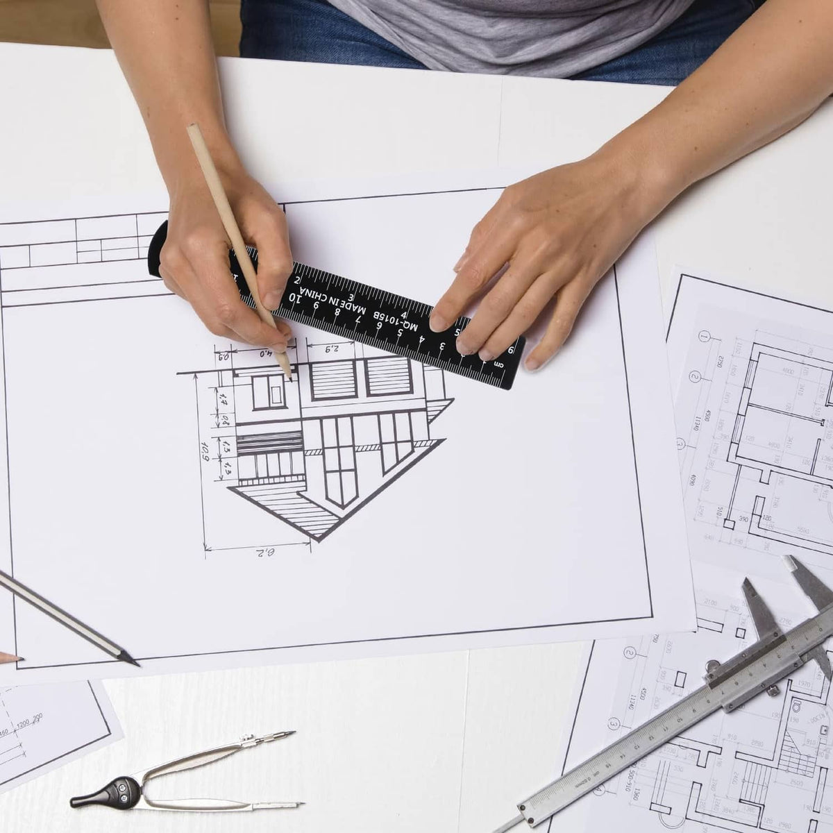 Black metal ruler with measurement scale over architectural floor plan