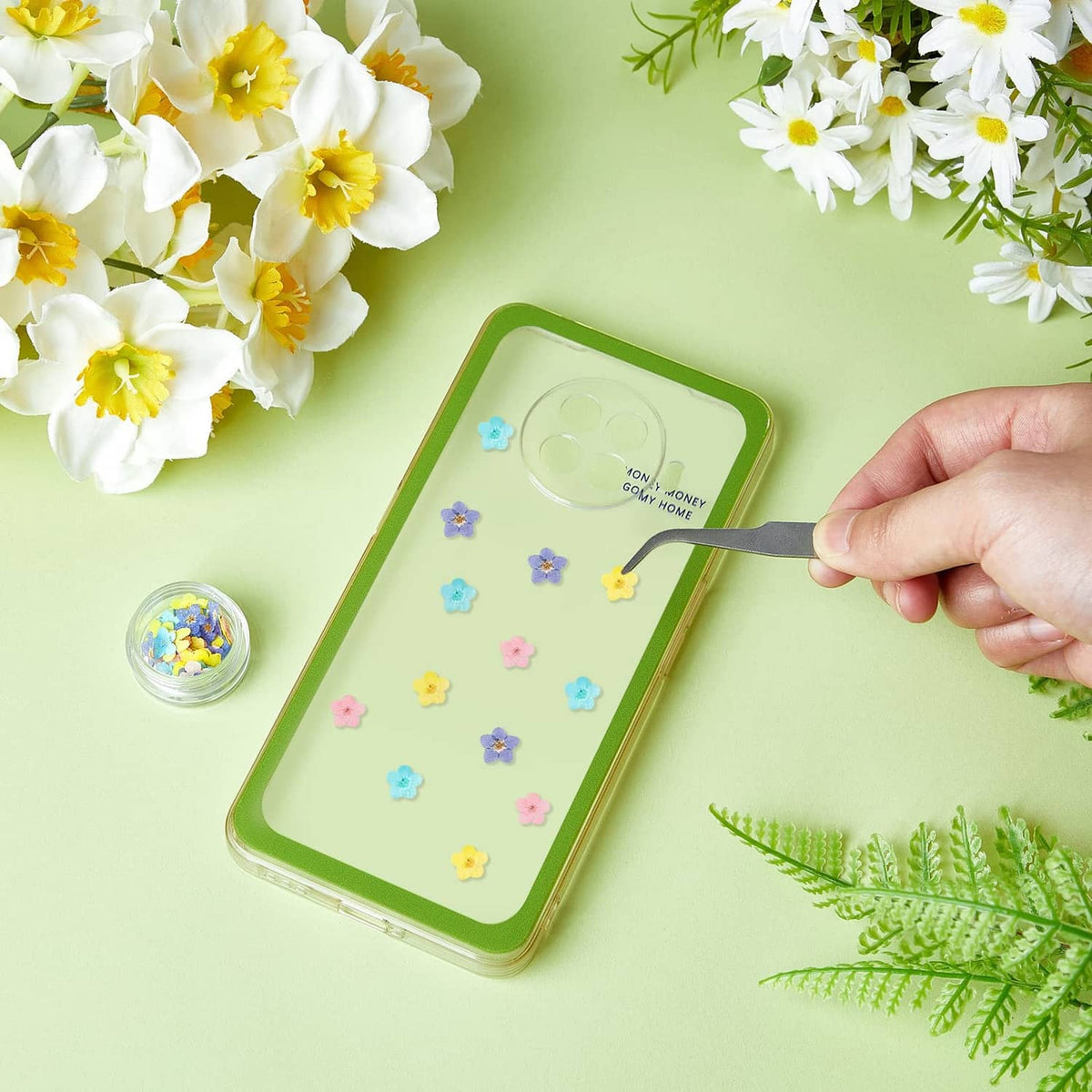 Pastel pressed-flower decals on a phone case, blue pink and yellow blooms