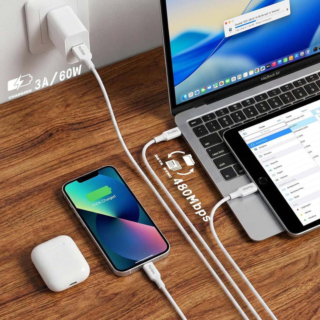 White USB-C charging cable connected to a phone and laptop on a desk