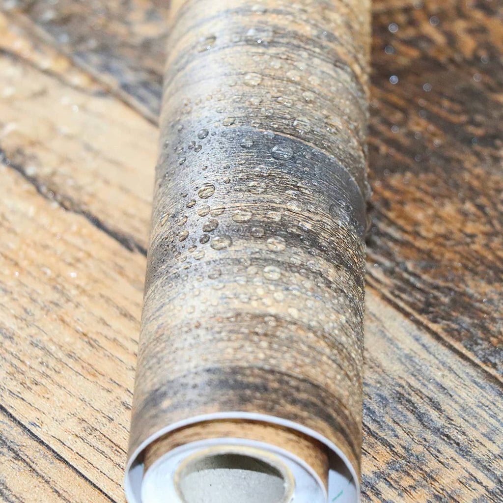 Faux wood peel-and-stick wallpaper roll with textured rustic plank pattern, visible curl edge