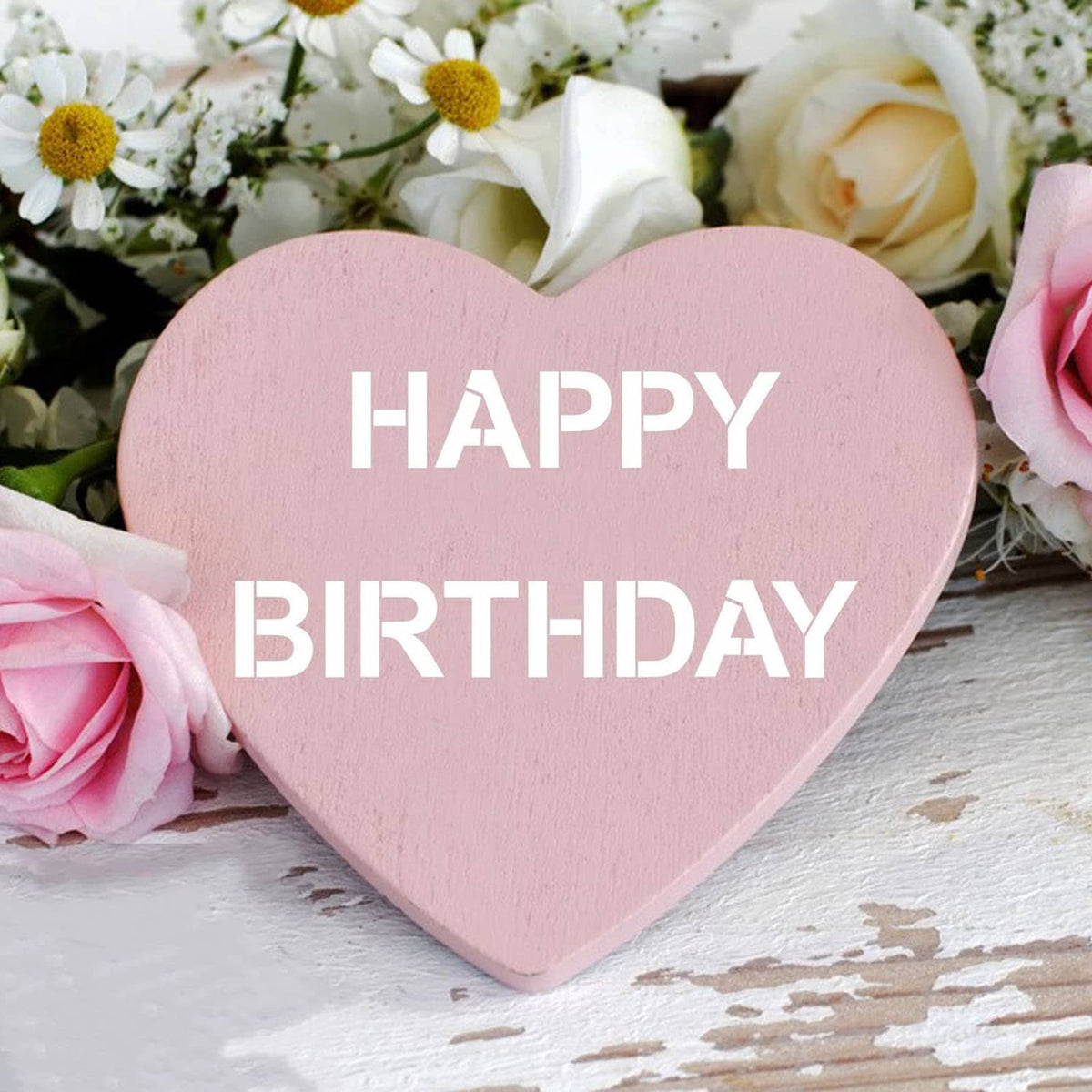 Heart-shaped pink sign with stencil-style text: HAPPY BIRTHDAY