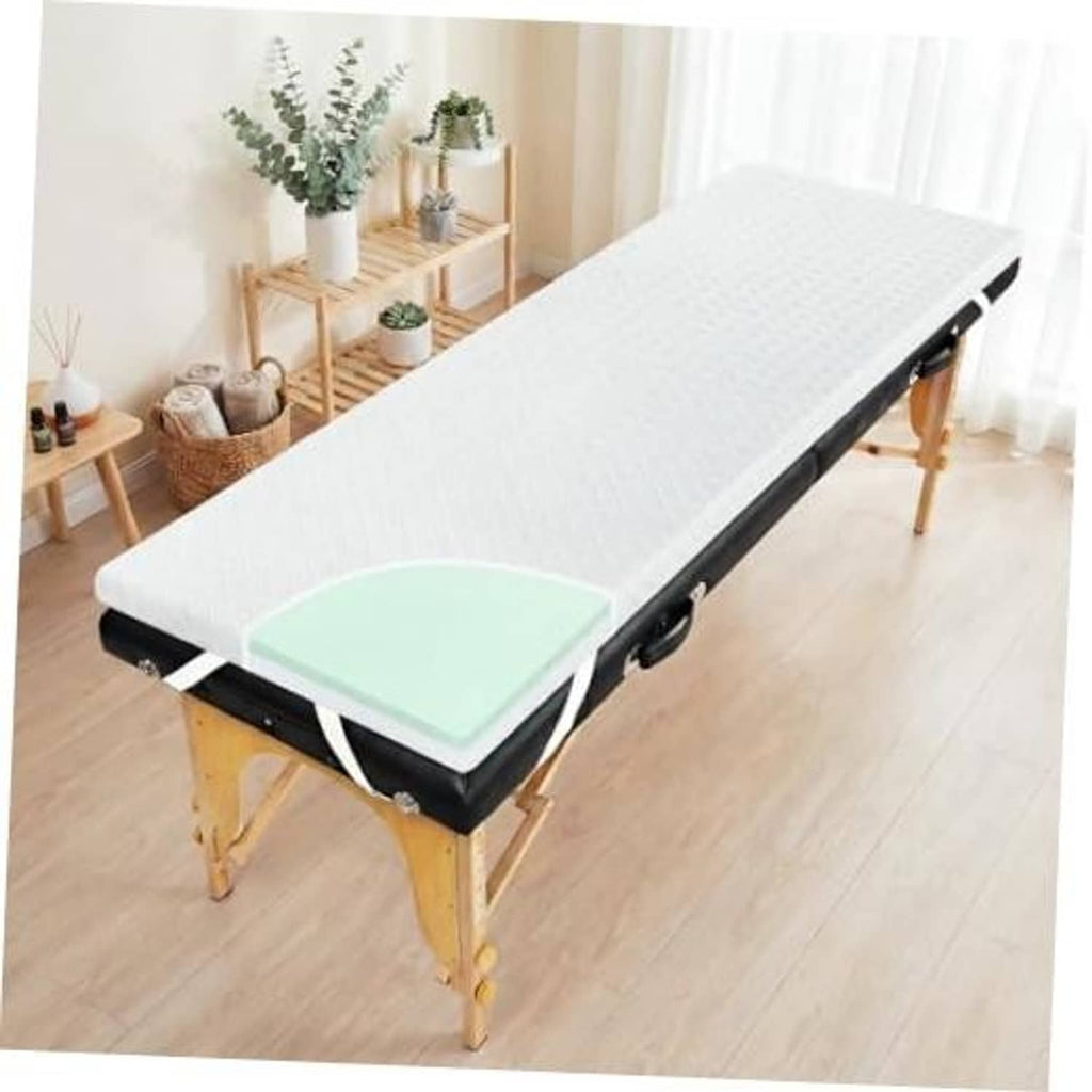 White memory foam massage table topper on black massage bed frame