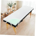 White memory foam massage table topper on black massage bed frame