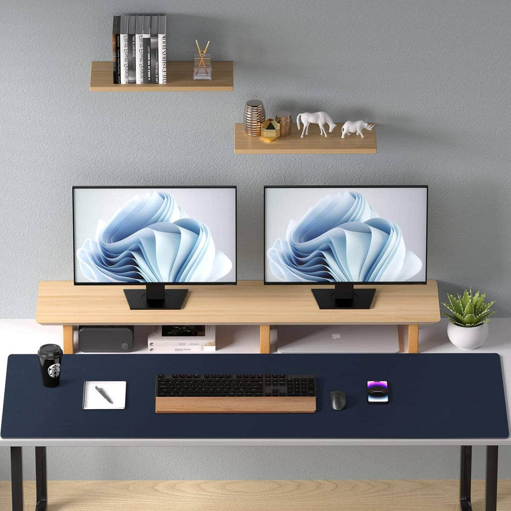 Dark blue desk pad protector covering a desk with laptop keyboards and office items.