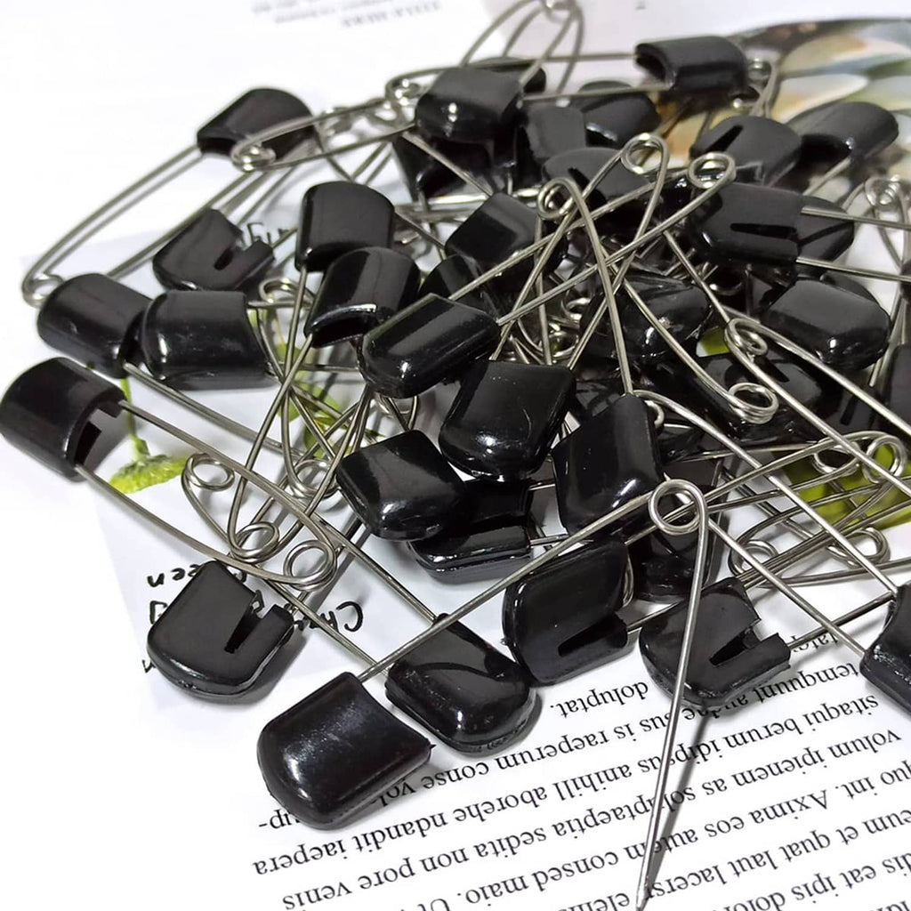 Pile of black plastic-head safety pins with metal needles and loop ring ends