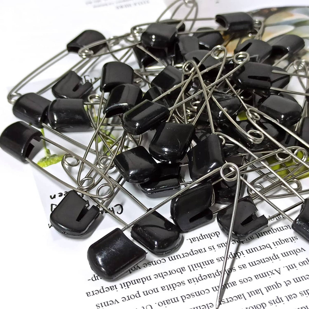 Pile of black plastic-head safety pins with metal needles and loop ring ends