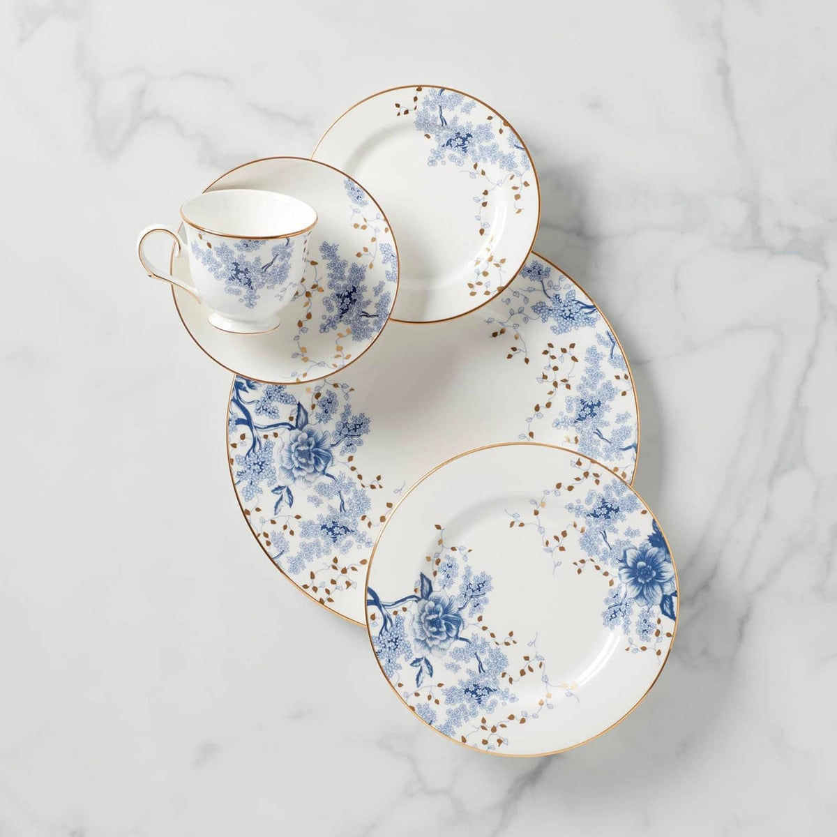 Porcelain place setting with blue floral teacup and saucer, and two matching plates