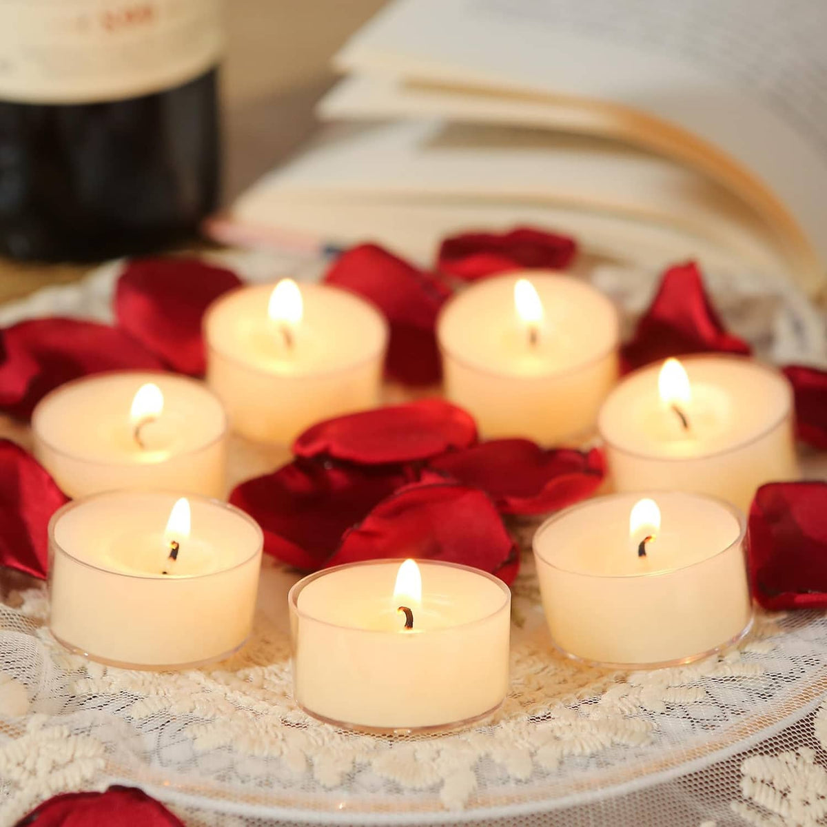 Cream beeswax tea light candles with red petals, several flames burning on lace