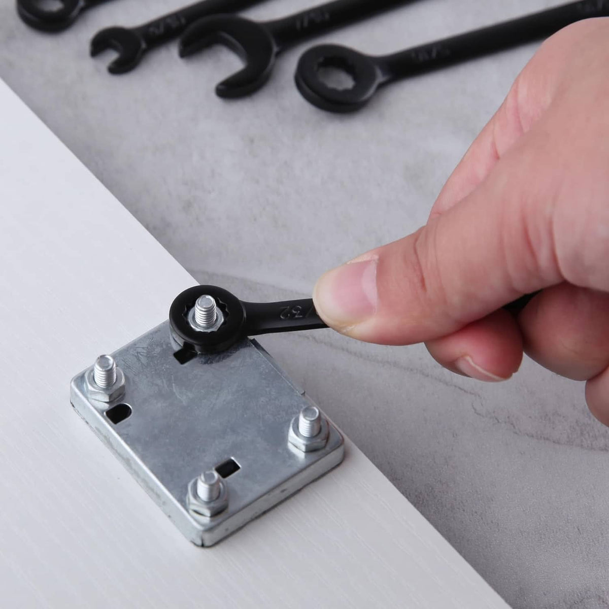 Black mini SAE wrench with hand tightening a bolt on a metal bracket