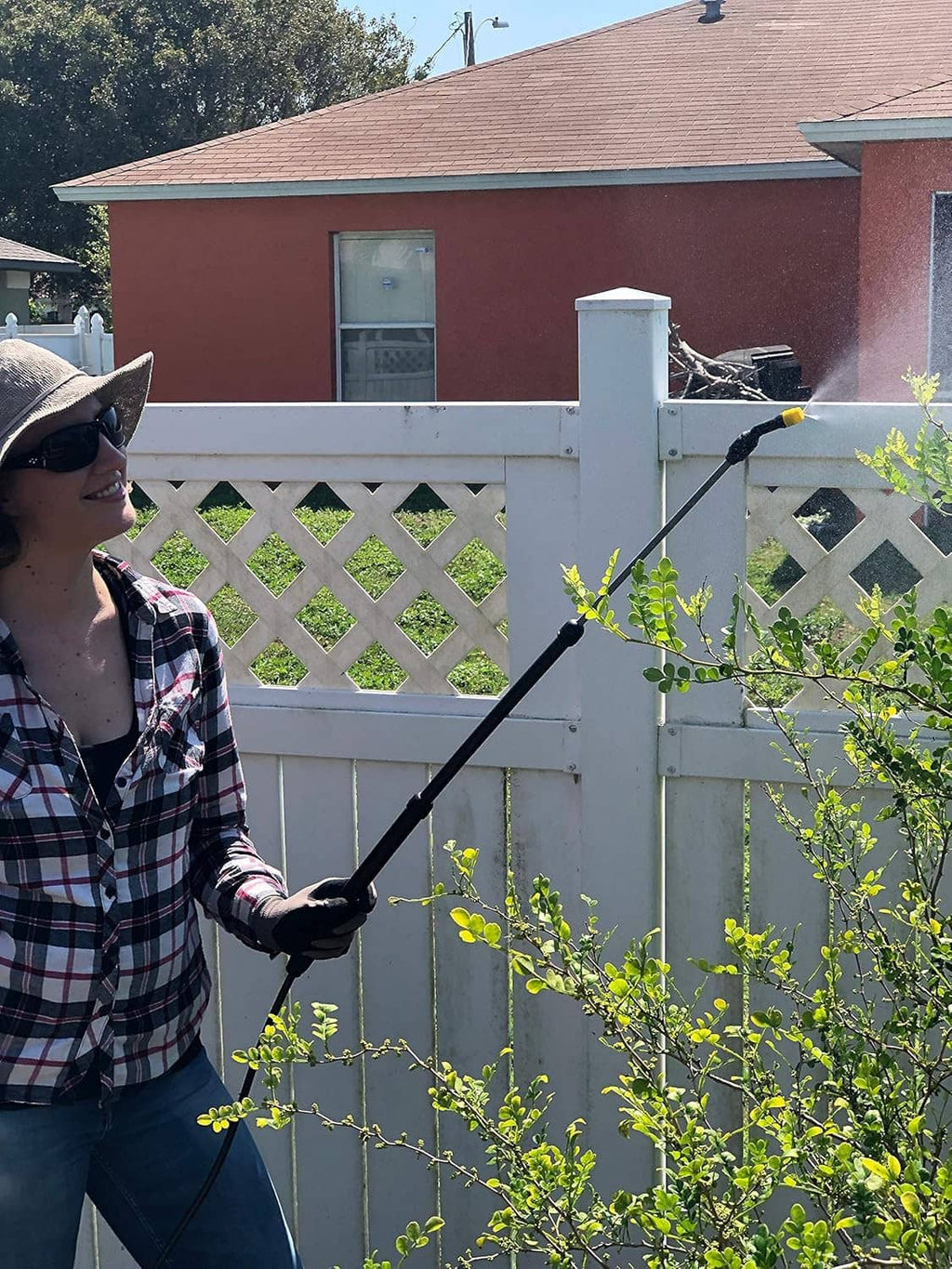 Sprayer wand from yellow tank spraying small green branches