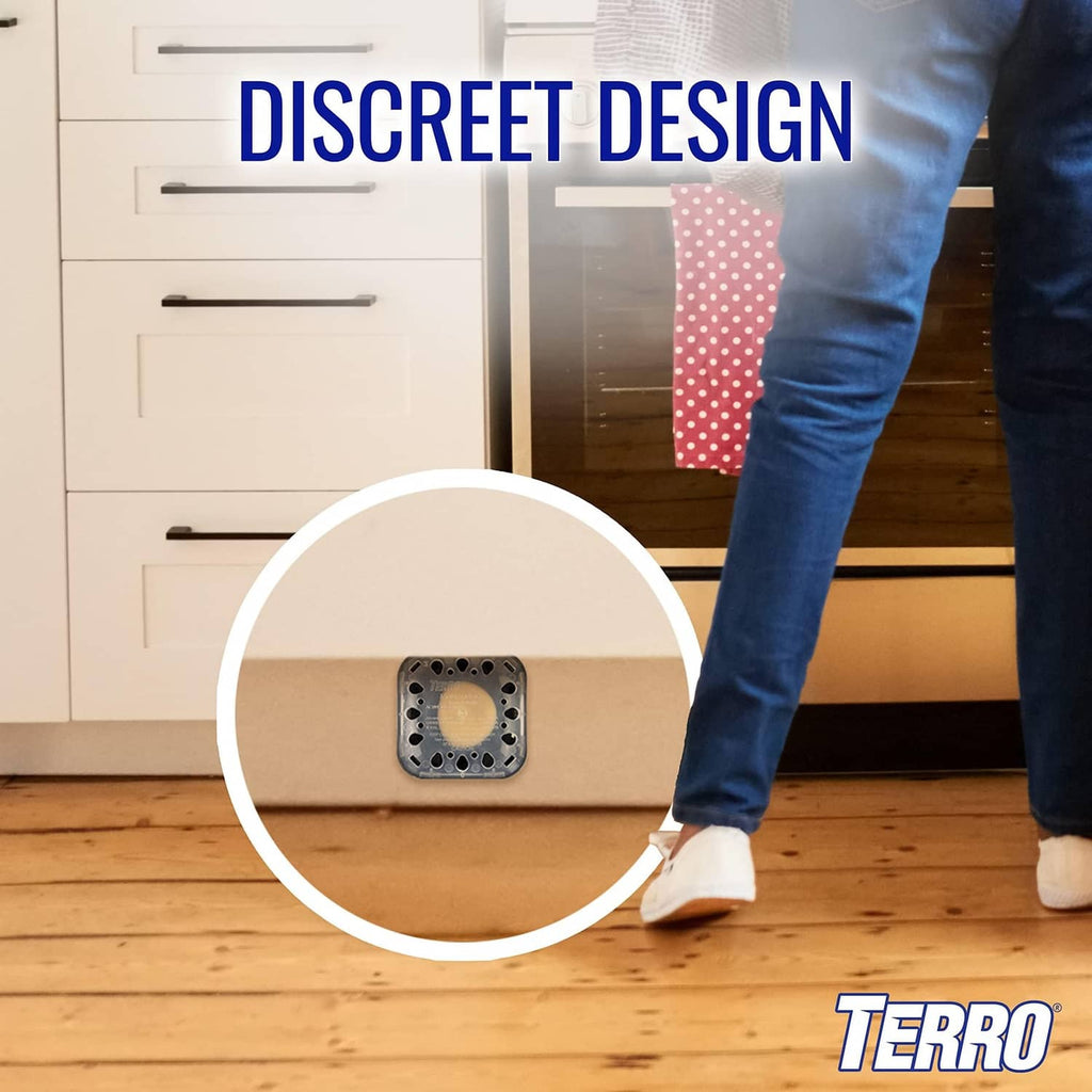 Black roach bait station with see-through top, discreetly placed on floor