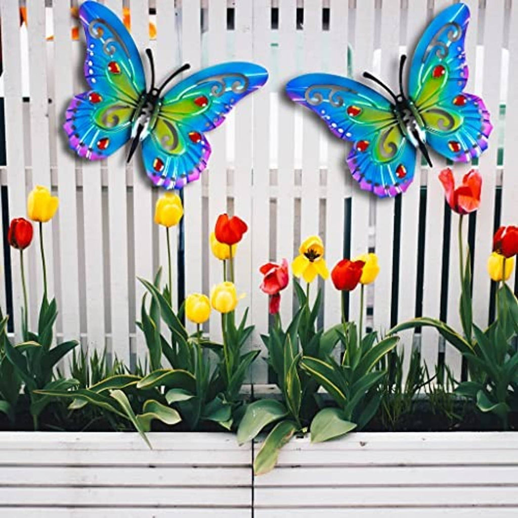 Two colorful metal butterflies with blue wings and red gem details on yard fence