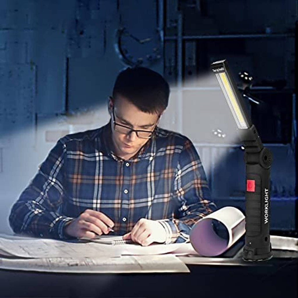 Black rechargeable LED work light with red power button used by a person working