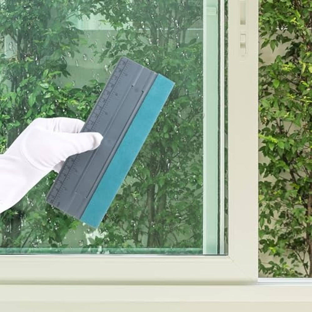 Vinyl squeegee with gray ruler and teal felt pad used on a glass window surface