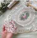 Beige lace placemat with ornate oval floral medallion and scalloped edge detail