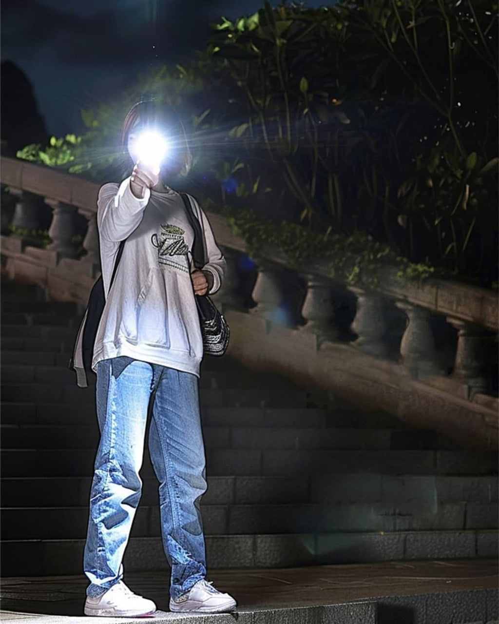 Handheld rechargeable flashlight casting bright white beam at night