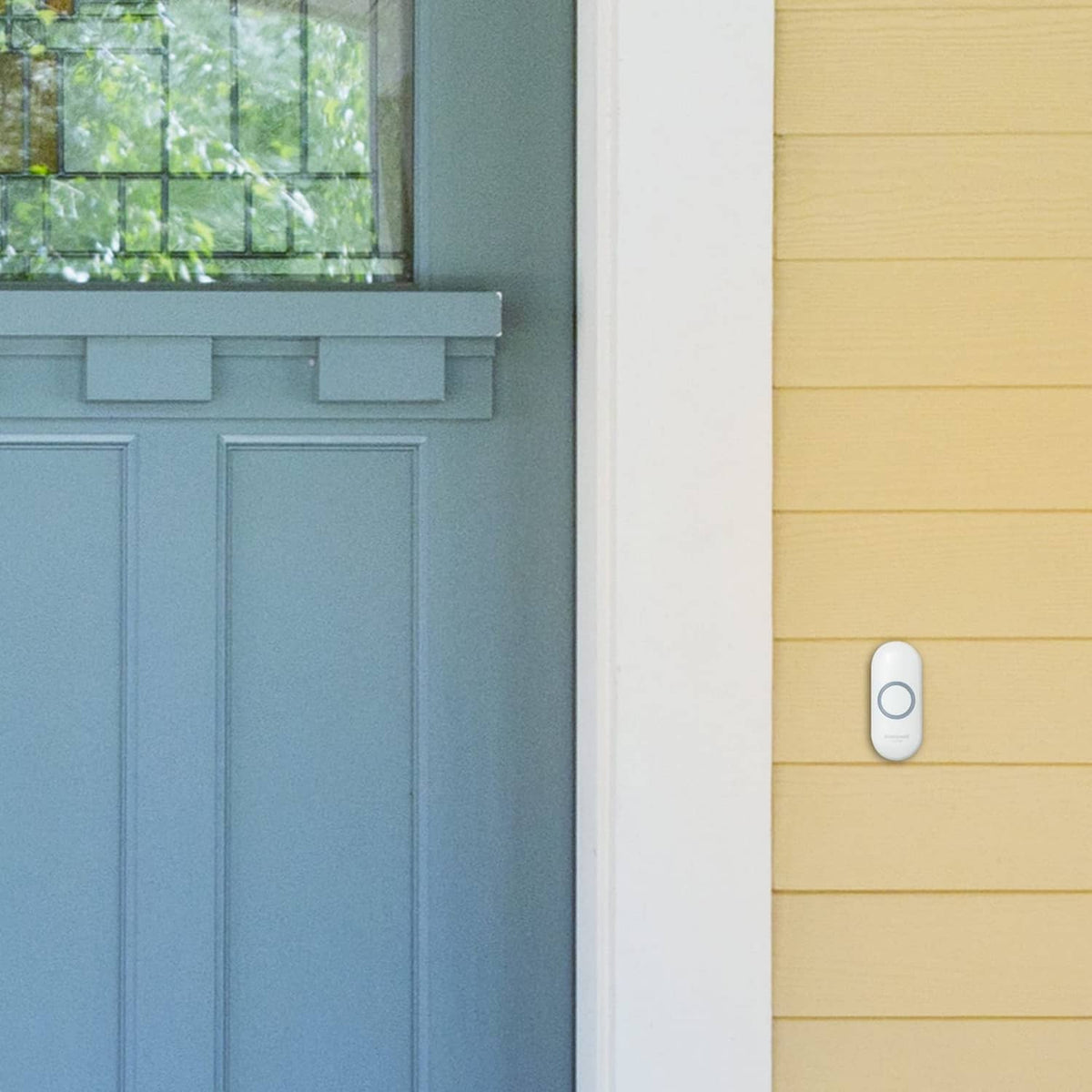 White wireless doorbell button with circular indicator on exterior siding wall