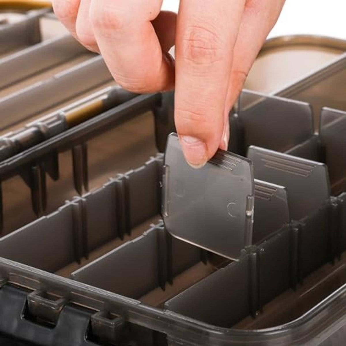 Waterproof fishing tackle box interior with sliding divider compartments and finger latch