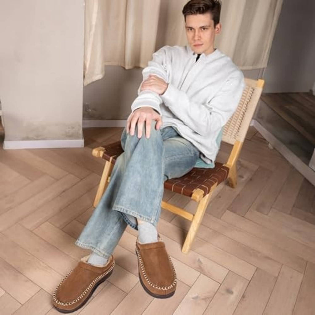 Tan moccasin slippers on a seated man; plush-lined slip-on house shoes
