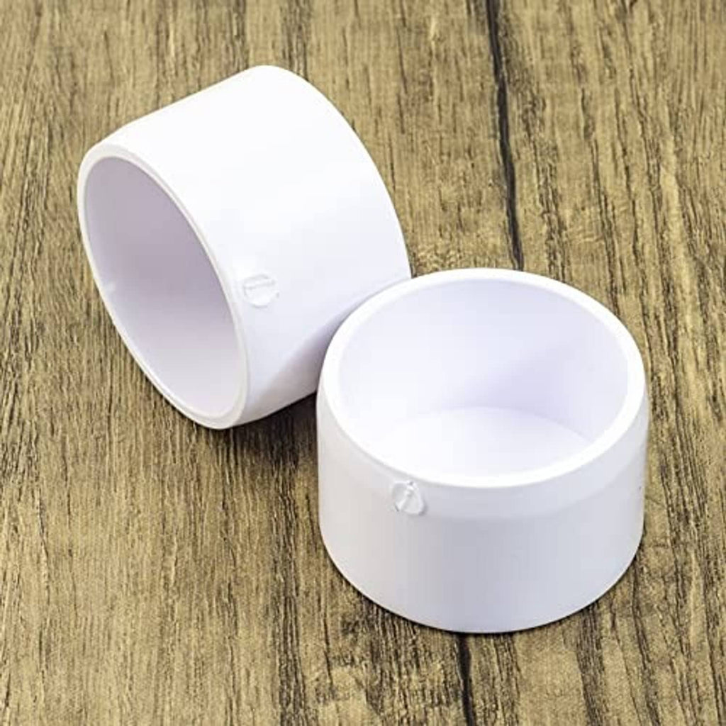 White PVC pipe end caps, 1-1/4 in pair; one upright, one on its side
