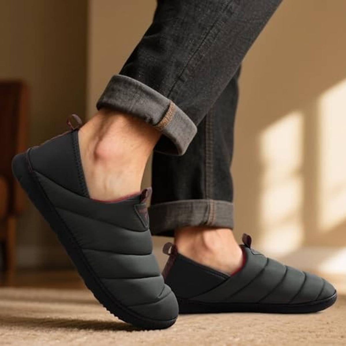 Men's dark grey quilted loafer slipper on foot with red inner lining.