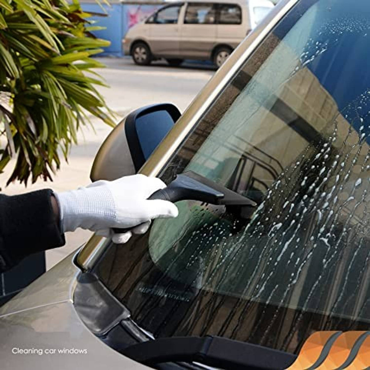 Black rubber squeegee cleaning a car window with a gloved hand