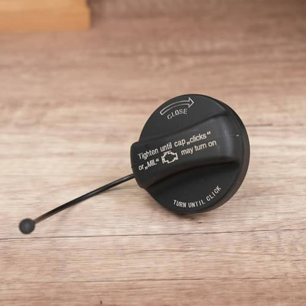 Black fuel tank filler cap with tether and printed instructions: CLOSE, TURN UNTIL CLICK