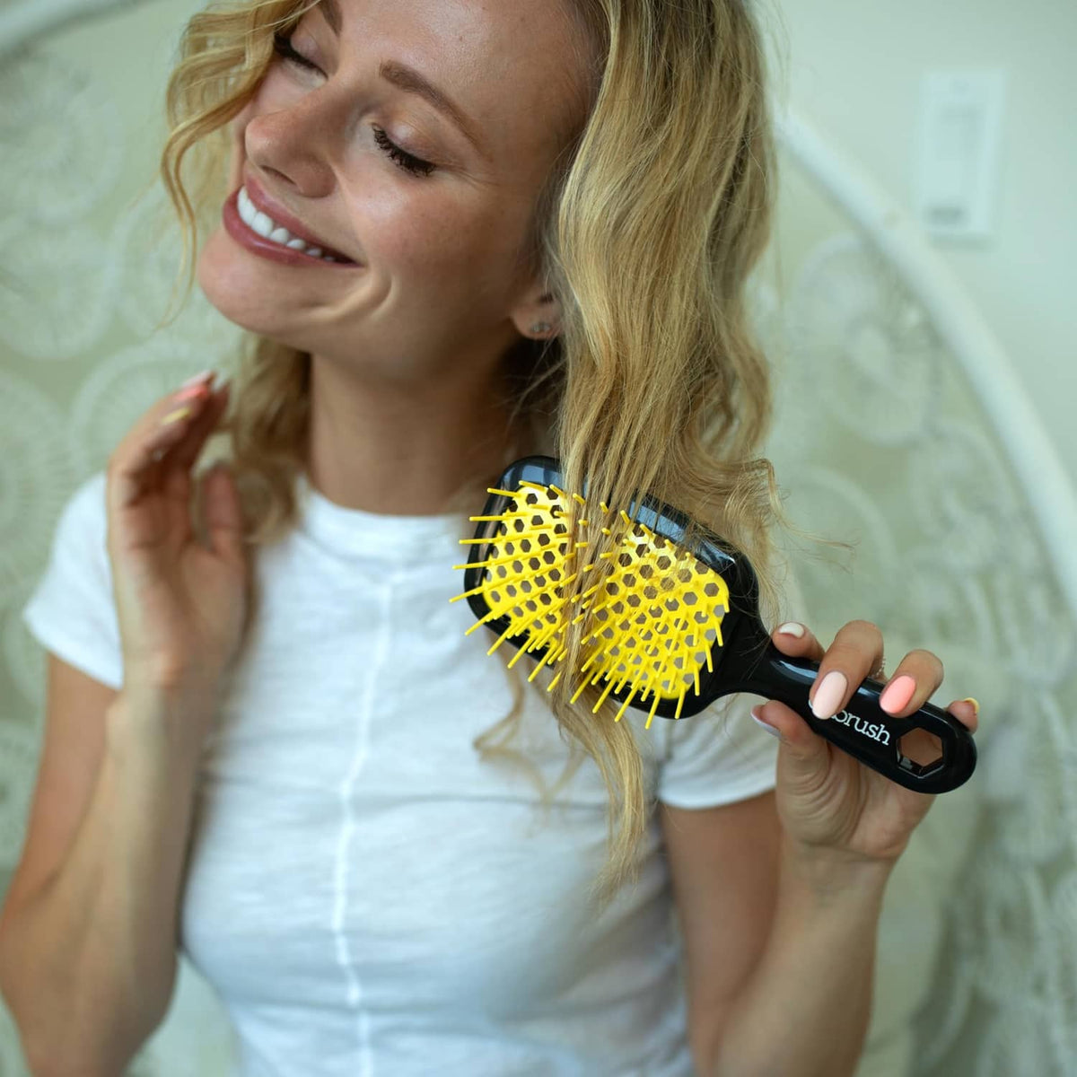 Black-handled detangling hair brush with yellow bristles used on blonde hair