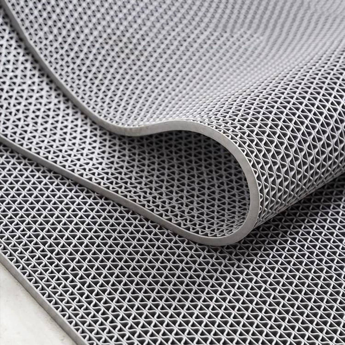 Dark gray PVC non-slip mat corner with rounded edge and lattice texture