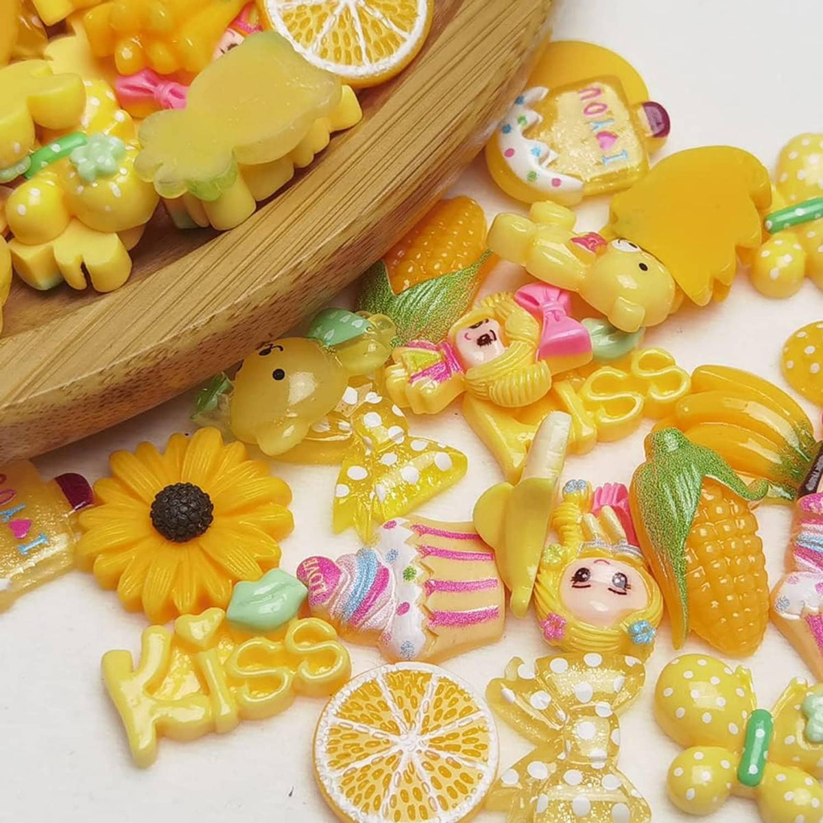 Yellow flatback resin buttons in fruit and animal shapes, on a wooden scoop