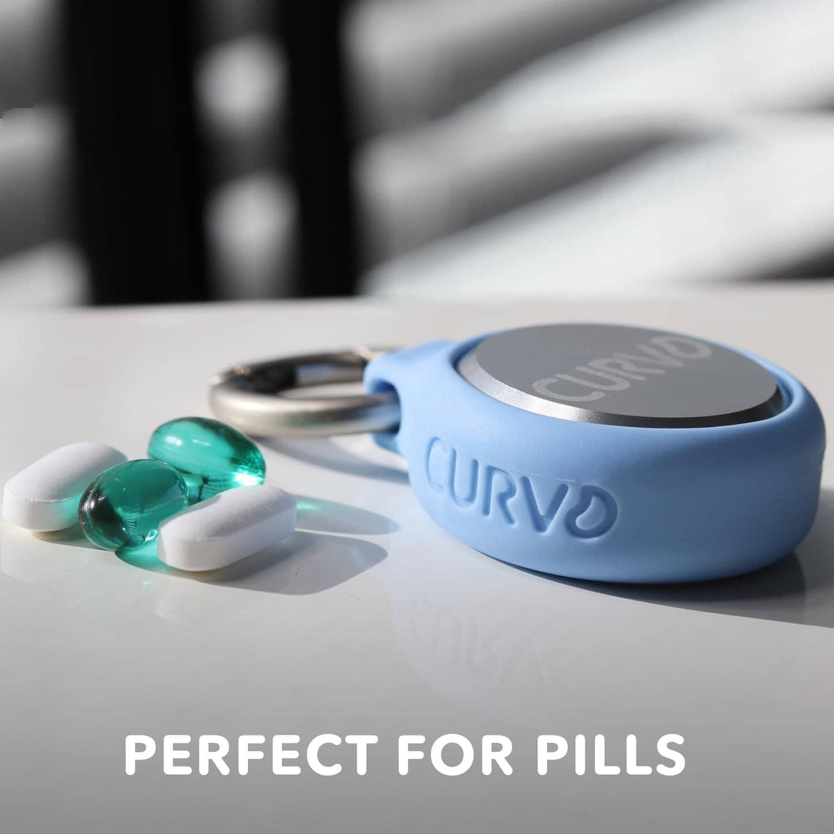 Blue keychain case with silver lid holding small green pills