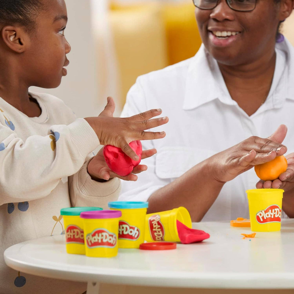 Assorted color modeling compound cans with red and orange clay on a table