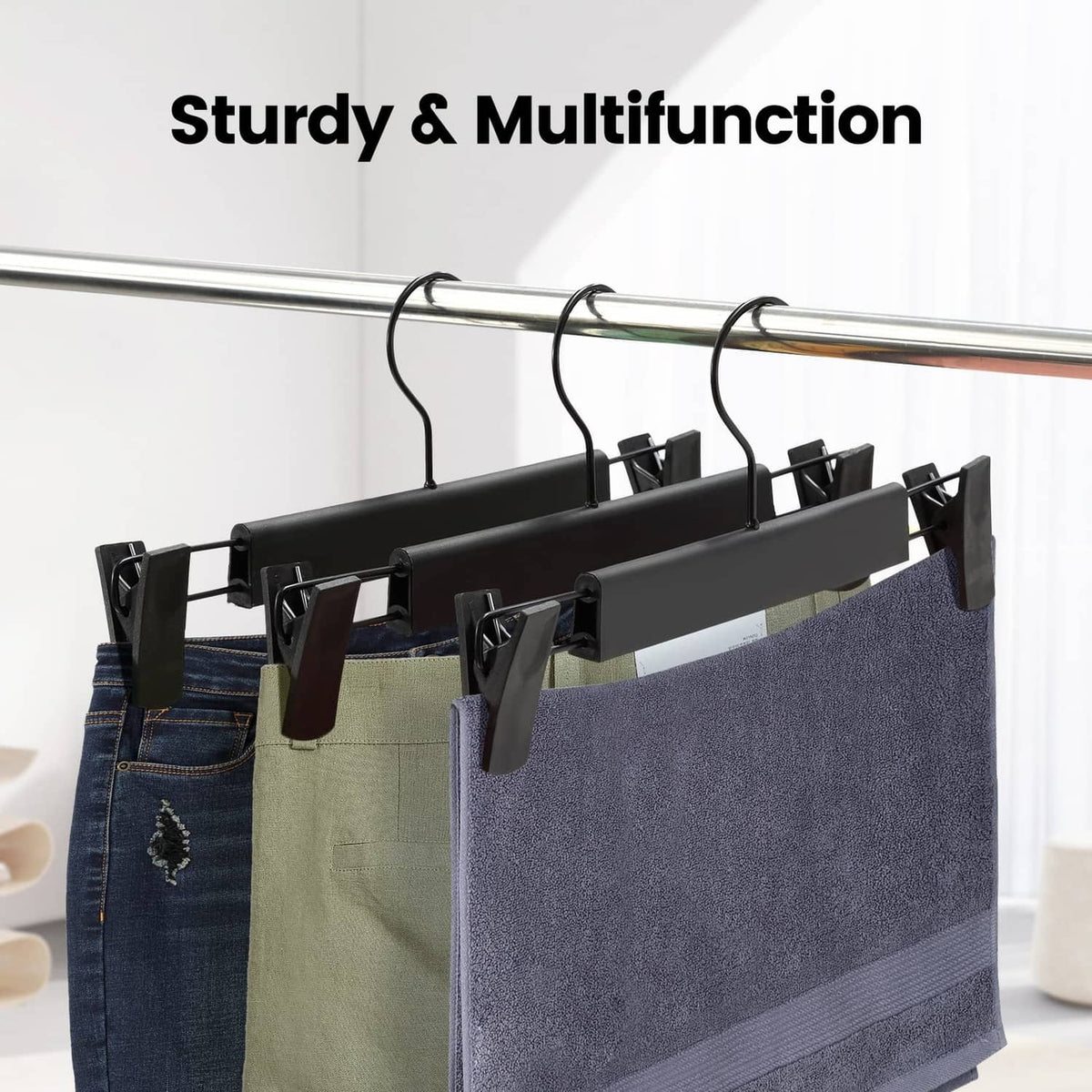 Black pants hanger rack with spring clips holding multiple garments on a bar