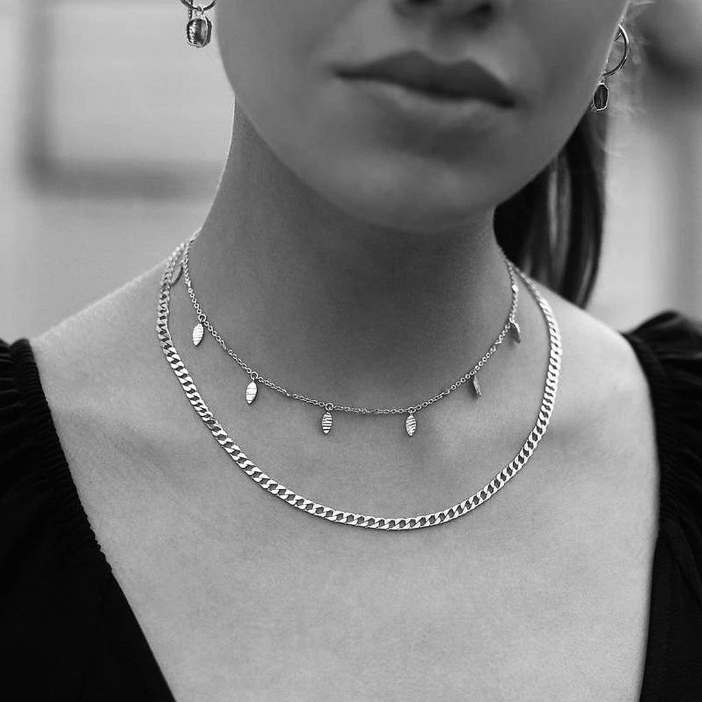 Silver Cuban link chain necklaces worn close to the neck on a model